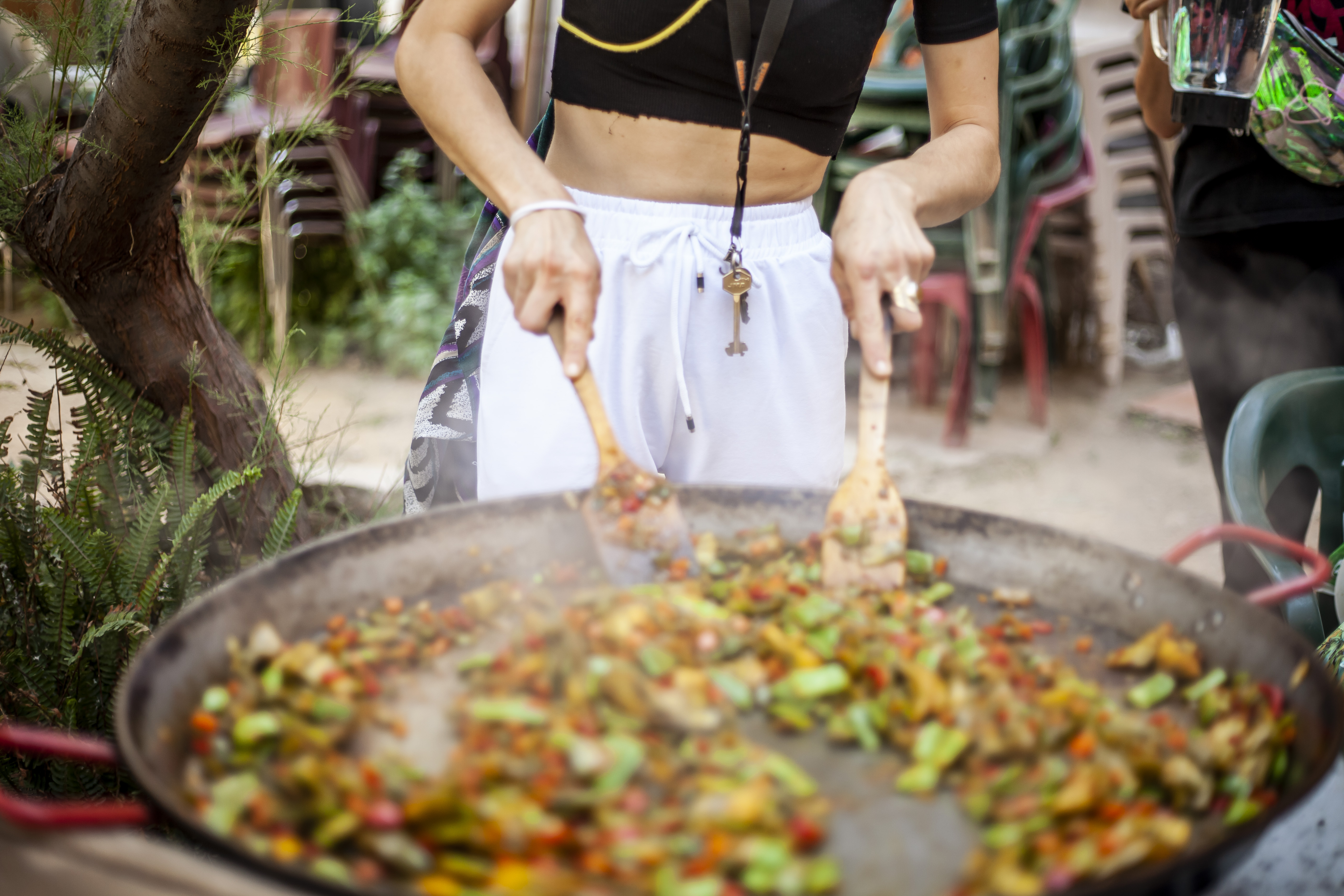 A person mixing ingredients in large paella pan