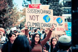 Protesters and woman holding poster that reads, "System change, not climate change"