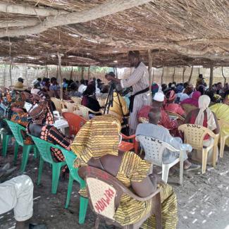 A community gathering with farmers sitting and in conversation.