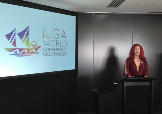 Photo de Sabrina Sanchez parlant à côté d'un écran de la réunion d'Ilga World.
